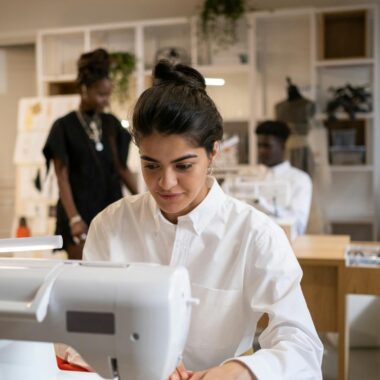 Focused designers creating garments in an atelier, using sewing machines and fabrics.