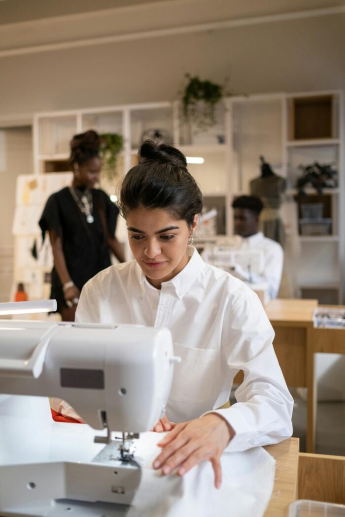 Focused designers creating garments in an atelier, using sewing machines and fabrics.